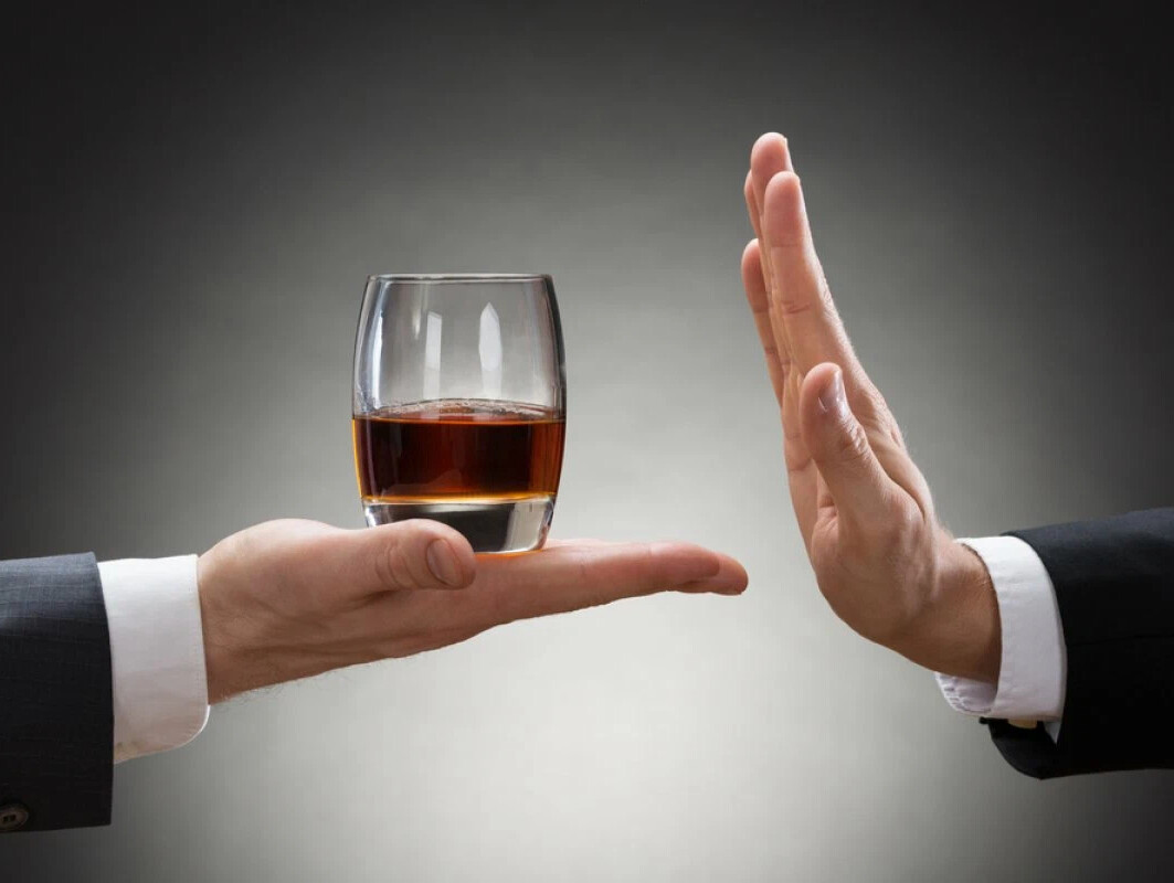 Одна рука предлагает стакан с алкоголем, а вторая жестом показывает стоп